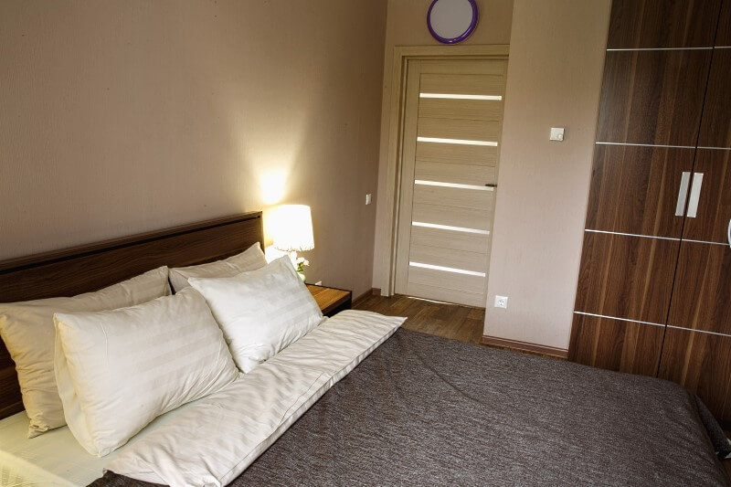 Удобные двуспальные кровати и шкафы для личных вещей в комнатах коттеджей за городом Омском